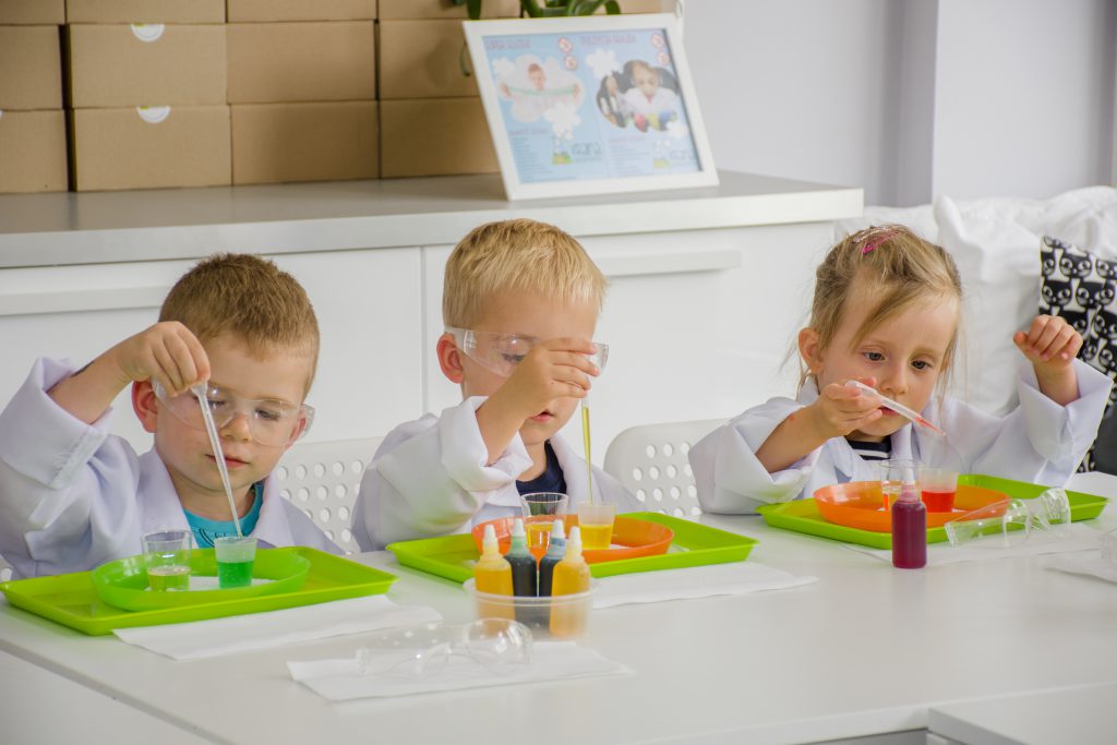 Przedszkolaki uczą się robić eksperymenty chemiczne, na zdjęciu 3 dzieci