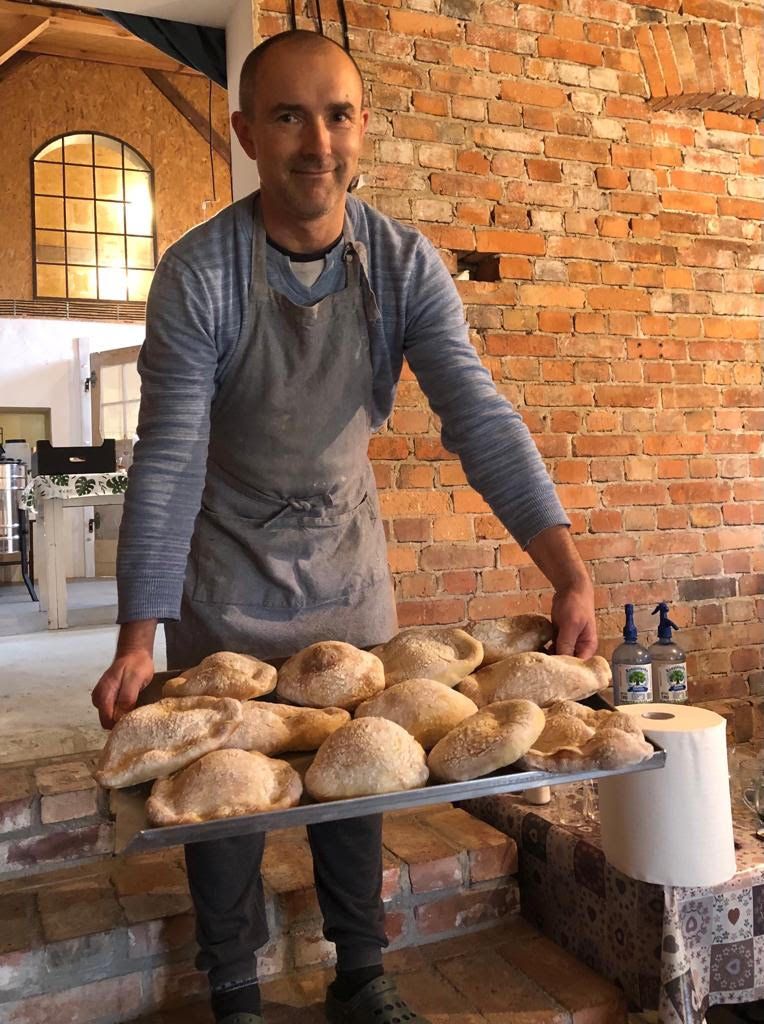 Warsztaty kulinarne - prowadzący zajęcia z tacą świeżo upieczonych chlebków