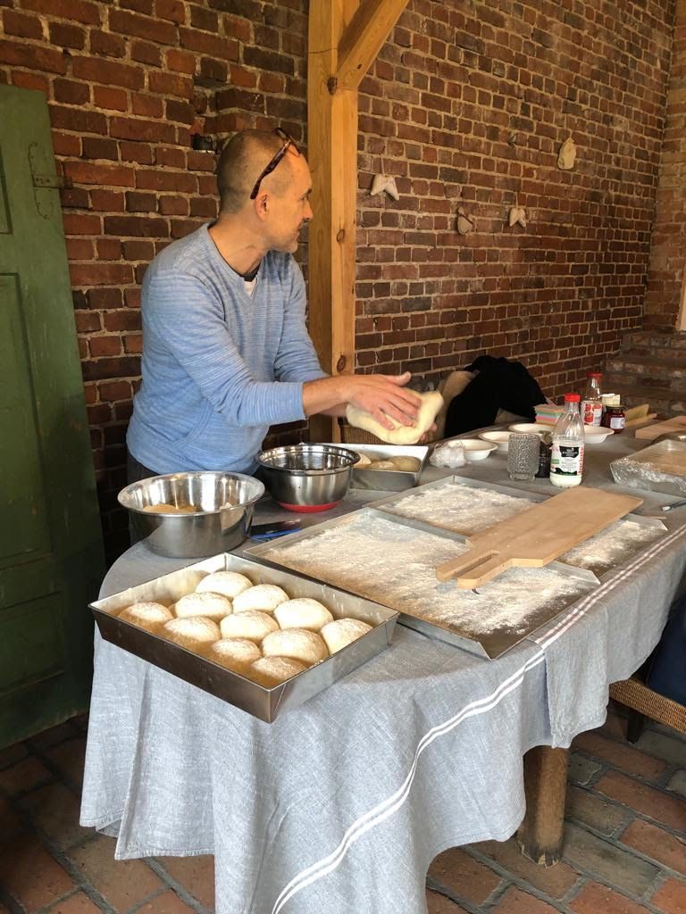 Warsztaty kulinarne - prowadzący zajęcia formuje bochenki chleba