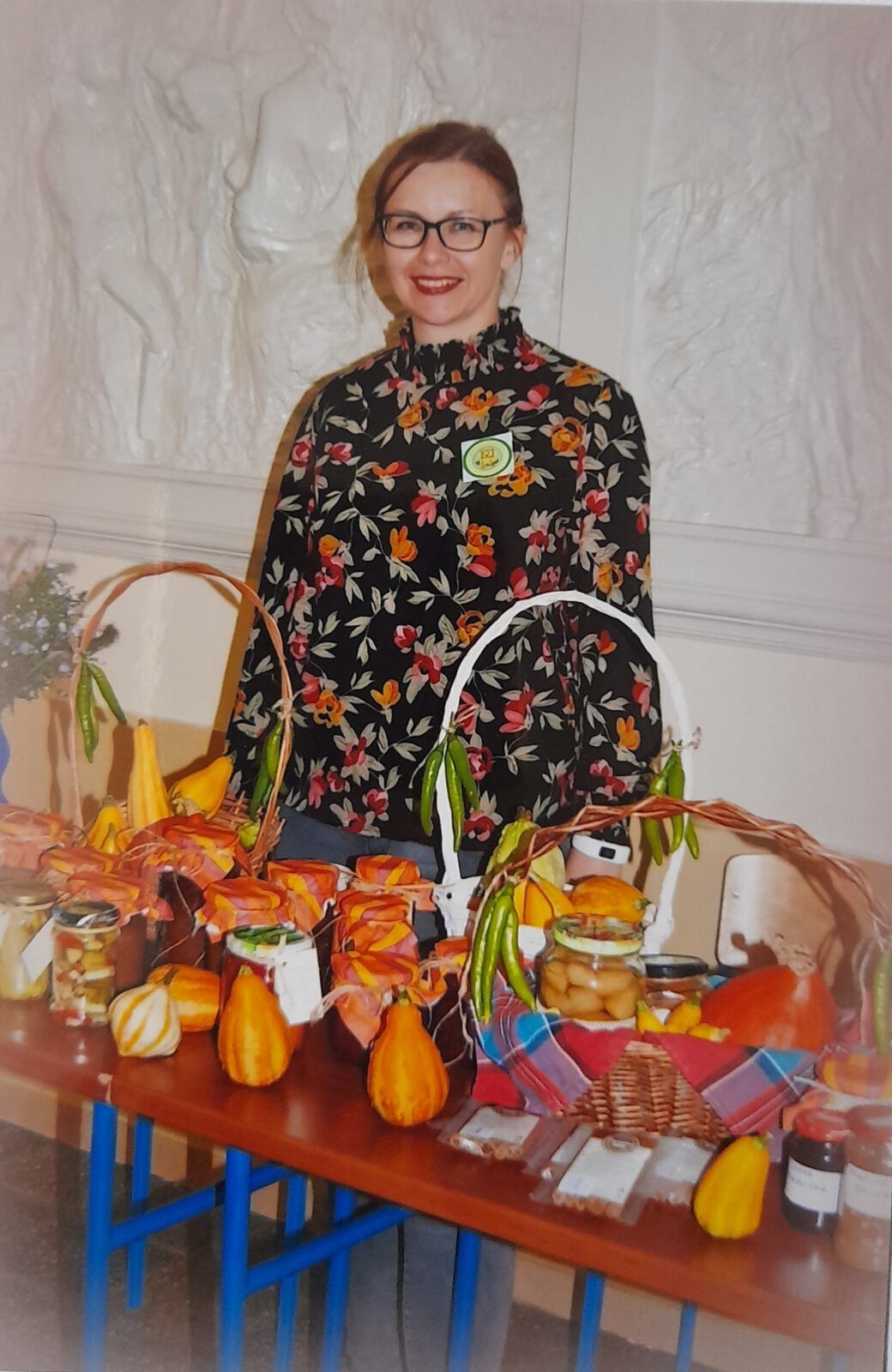 Nauczycielka SP21 stoi przy stole zastawionym jesiennymi przetworami