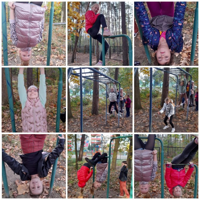 Uczniowie w przyszkolnym lesie bawią się na placu zabaw, np. wiszą do góry nogami na metalowych drabinach