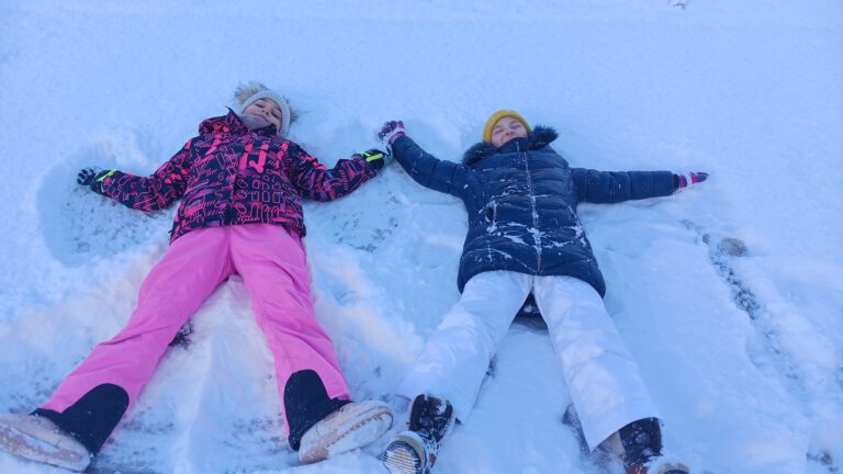 dwie uczennice robią anioła na śniegu