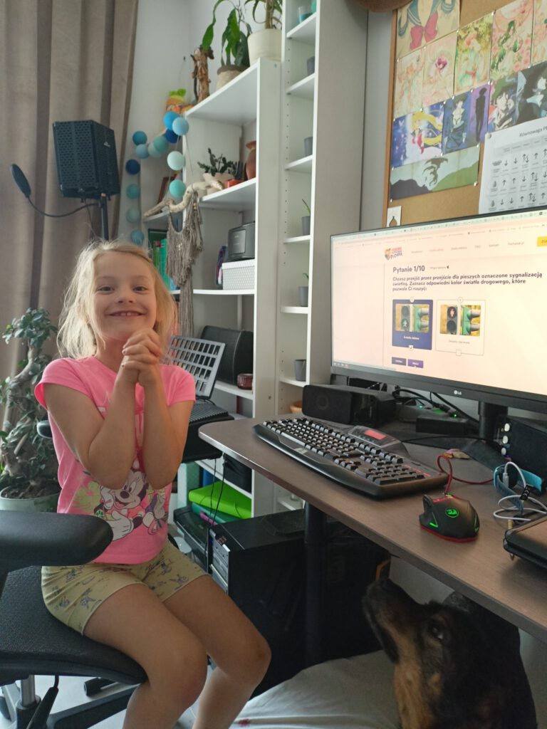 uśmiechnięta dziewczynka rozwiązuje test w komputerze