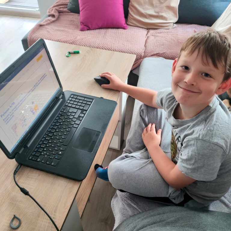 uśmiechnięty chłopiec rozwiązuje test w komputerze