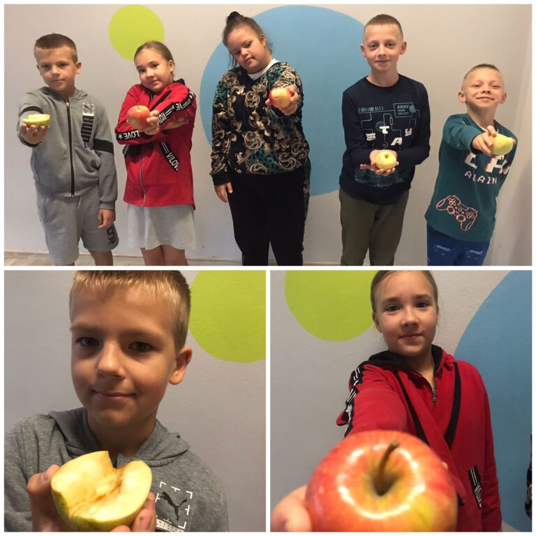 uczniowie pozują do zdjęć trzymając jabłka