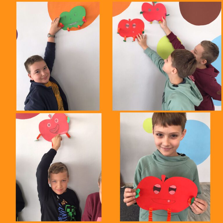uczniowie pokazują owoce które wykonali na zajęciach plastycznych, kolorowe gruszki i jabłka