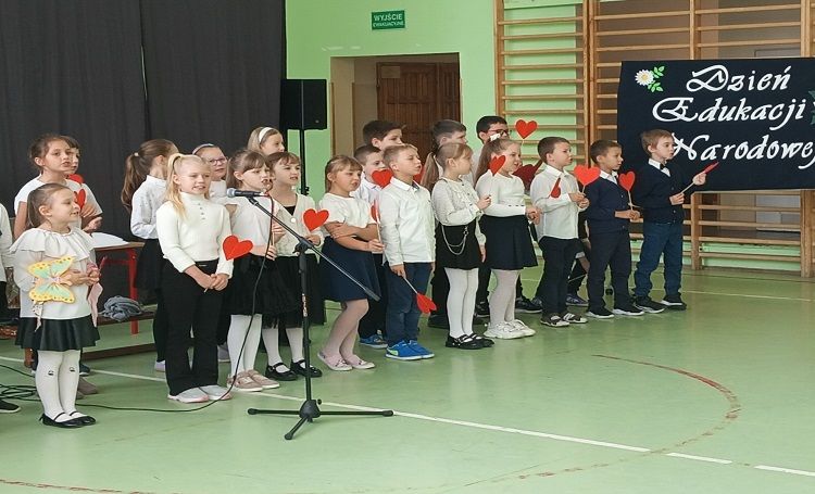 dzieci na sali gimnastycznej, ubrane na galowo w czasie apelu