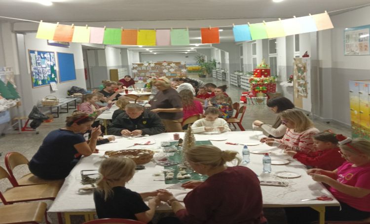 rodzice i dzieci siedzą przy stołach i przygotowują bożonarodzeniowe ozdoby